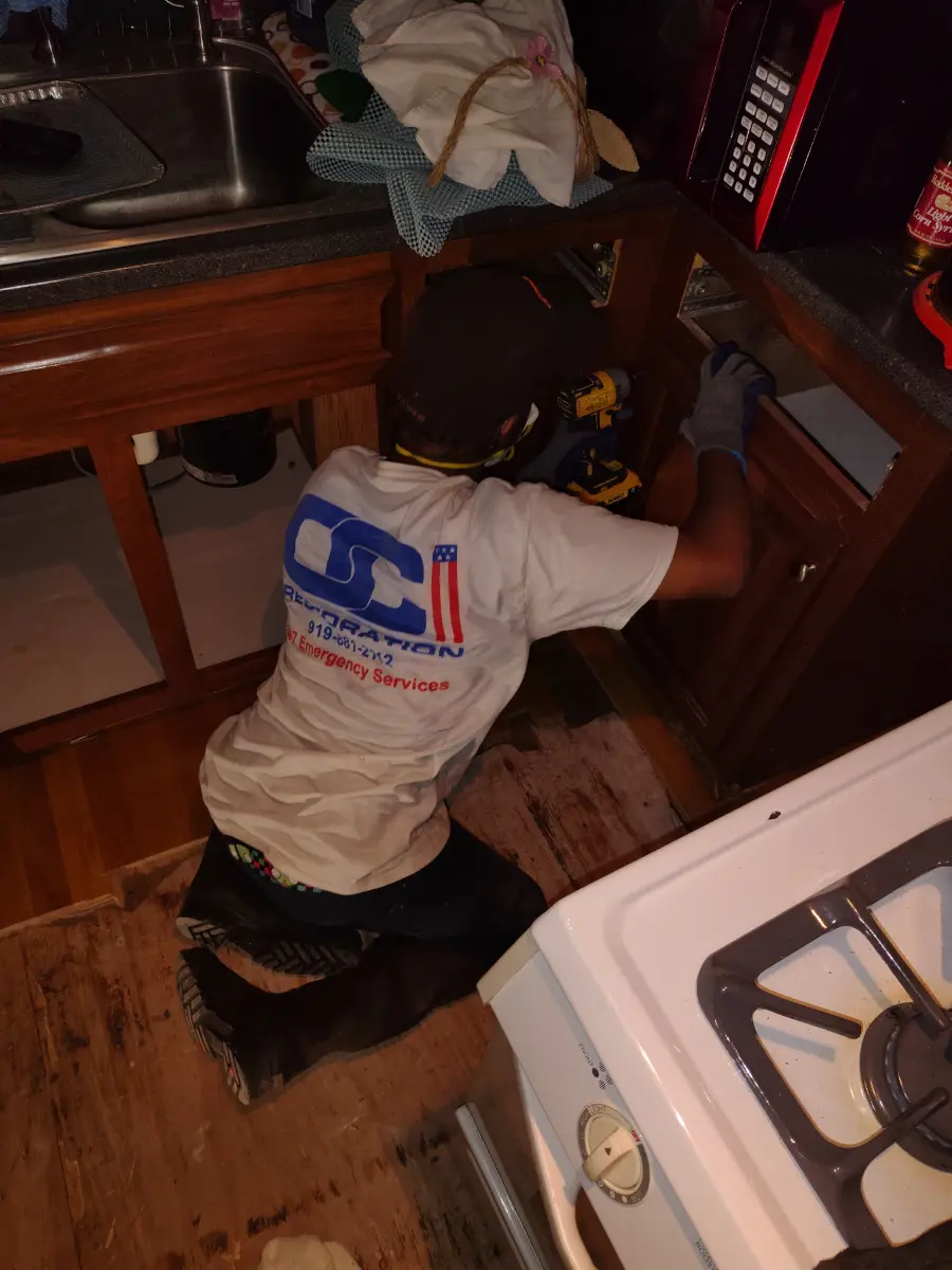 OCI Restoration technician opening cabinetry to trace hidden moisture during a mold assessment
