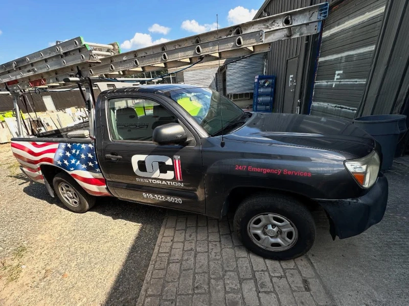 Pickup truck with American flag design on the rear and ladders mounted on top. water damage restoration company